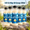 Năm chai Cốt Cá Mập SH Group 330ml trưng bày bên hồ nước ngọt, phía trước có cốc dung dịch cùng màu.